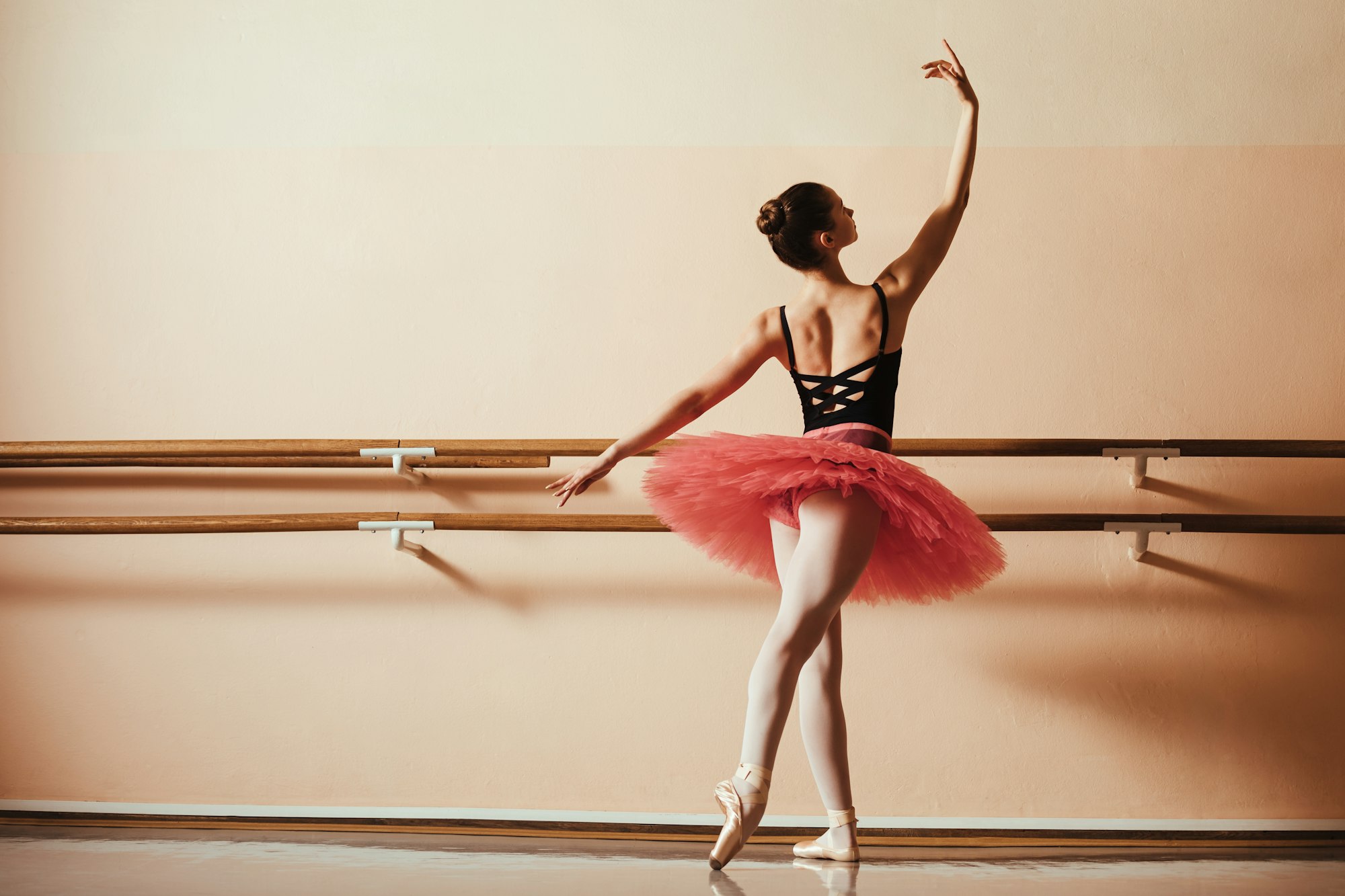 Back view of graceful female ballet dancer at ballet studio.